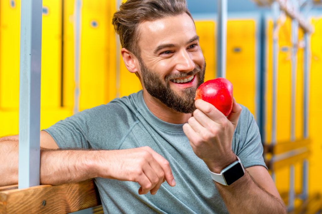 A smiling man eating an apple, representing the positive impact of nutrition and exercise on mental health.