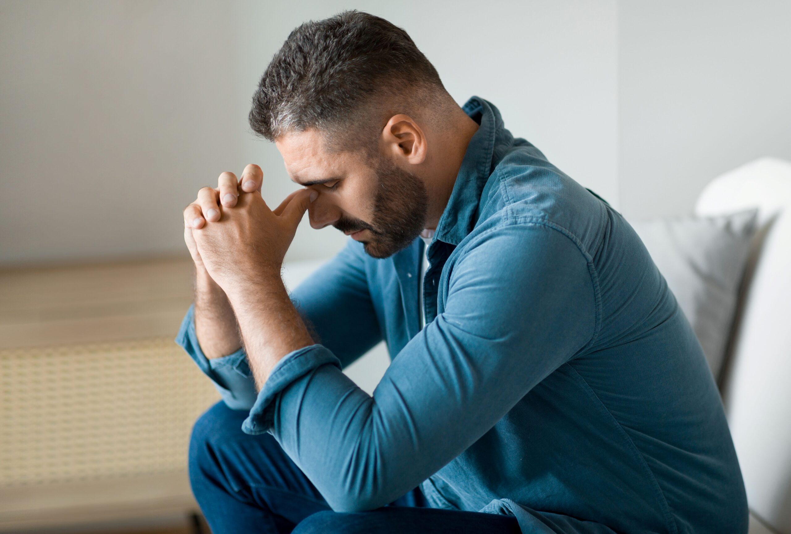 A depressed man sitting alone on a bench, symbolizing the need for reducing stigma around men's mental health.