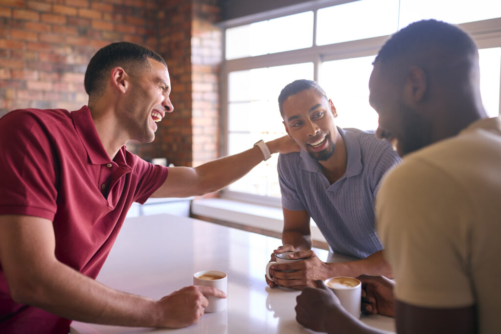 A group of men sitting together, engaging in an open conversation about men's mental health.

